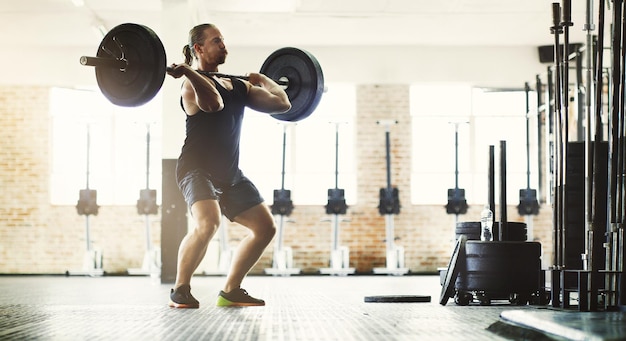 写真 フィットネストレーニングとトレーニング運動と健康のためのジムでバーベルを持つ男性スポーツウェルネスと男性アスリートまたは強力なボディービルダーが体の筋力と筋力運動のために重量を持ち上げる