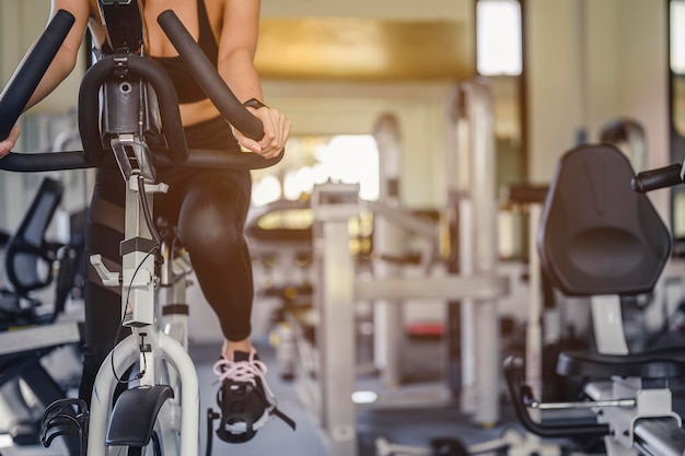 Fitness ,workout, gym exercise ,lifestyle  and healthy concept. Front view of woman workout with bike. Women exercise working out in the gym for healthy lifestyle on bike at sunset.