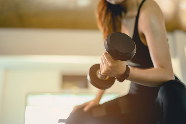 Fitness ,workout, gym exercise ,lifestyle  and healthy concept. Women exercise by dumbbells at the indoor gym for good health at sunset.