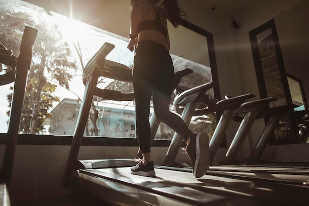 Fitness, workout, gym exercise, lifestyle and healthy concept. Women walking on the treadmill in the gym for good health and strength at sunset.