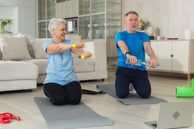 Fitness workout training senior adult mature healthy fit couple doing sports exercise on yoga mat on