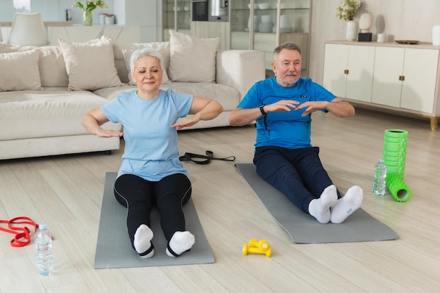 Fitness workout training senior adult mature healthy fit couple doing sports exercise on yoga mat on