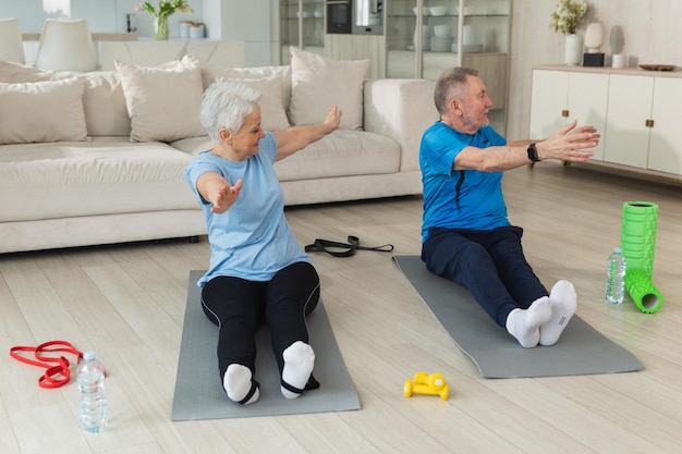 Fitness workout training senior adult mature healthy fit couple doing sports exercise on yoga mat on