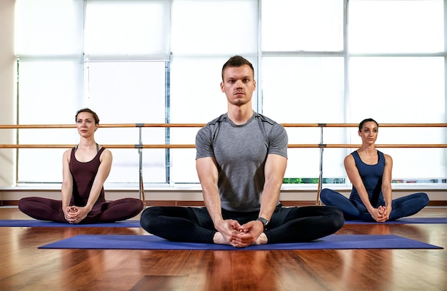 Fitness yoga and healthy lifestyle concept group of people
doing lotus seal gesture and meditating in seated pose at
studio