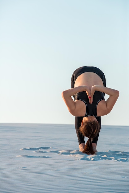 Fitness yoga vrouw die zich uitstrekt op zand fit vrouwelijke atleet doet yoga pose