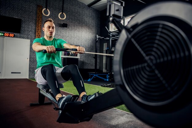 Fitness young man using a rowing machine in the gym