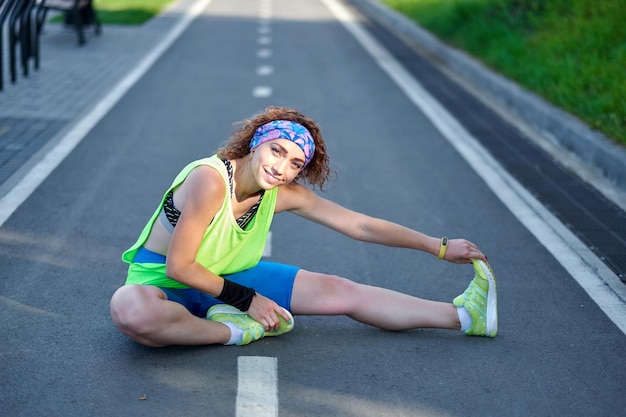Fitness young woman stretching legs after run outdoors after run