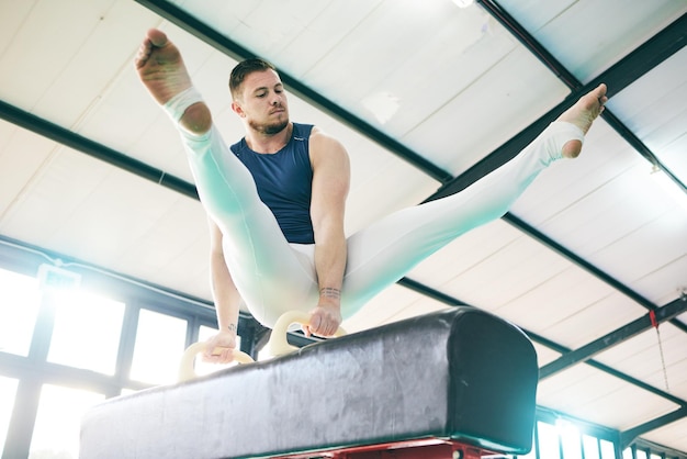 Fitnessgymnastiek en man op een evenwichtsbalk voor het trainen van cardio en kracht in de sportschool Atletische man en acrobaat oefenen snelheidscontrole en sportroutine voor spierkracht of uithoudingsvermogen