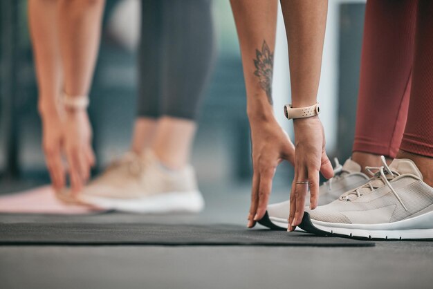 Fitnesshanden of vrienden die de benen strekken in de sportschool om het lichaam op te warmen of spieren te ontspannen voor trainingsoefeningen Vrouwenfocus of gezonde sporters trainen samen ter ondersteuning van inspiratie of motivatie