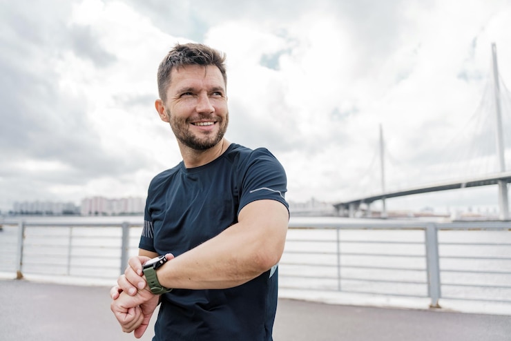 Foto fitnesshorloge en een man een sportieve man in sportkleding lichaamswarming voor fitness hardlopen
