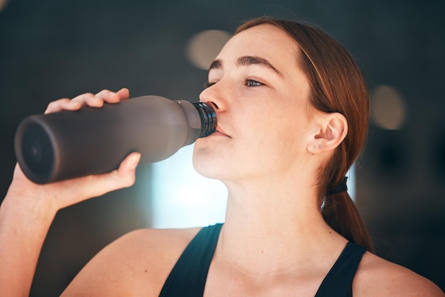 Fitnesshydratatie en drinkwater voor vrouwelijke atleten voor dorst, wellness en gezondheid in een trainingsstudio Sportenergie en jonge vrouw die geniet van een gezond koud drankje na een training of oefening