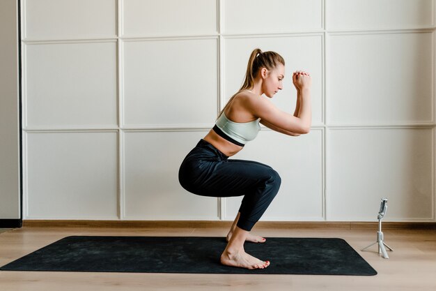 Fitnessinstructeur die live sporttraining op telefoon voor online cliënten thuis opnemen