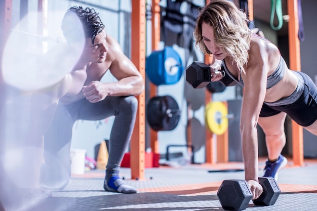 Fitnessinstructeur met vrouw die halterdrukoefeningen doet in de sportschool