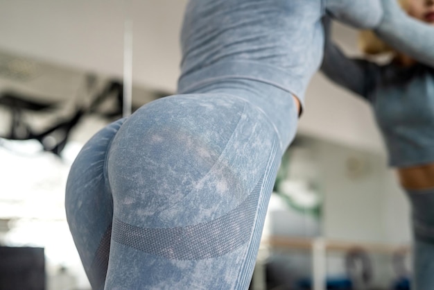 Fitnessmodel in legging met mooie billen poseren in de sportschool