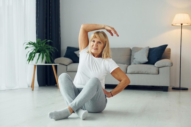 Fitnessoefeningen doen Senior vrouw met blond haar is thuis