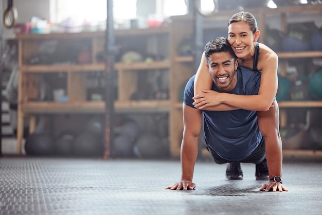 Fitnesspaar dat plezier heeft terwijl de man push-ups doet en samen traint in de sportschool Gezonde fitte en atletische vrienden spelen en gek terwijl ze genieten van een trainingssessie met teamwork in een gezondheidsclub