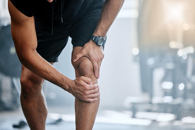 Fitnessruimte en mockup man met kniepijn en medisch noodgeval door trainingsblessure in sportstudio Oefening gezondheid en welzijn bodybuilder met hand op beenspierpijn voor verlichting tijdens training