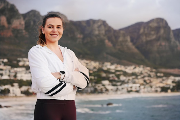 Fitnessstrand en portret van een vrouwelijke atleet na het doen van cardiotraining aan de oceaan in Australië Gelukkige glimlach en gezonde vrouwelijke hardloper die een buitenoefening doet of traint in de natuur aan zee