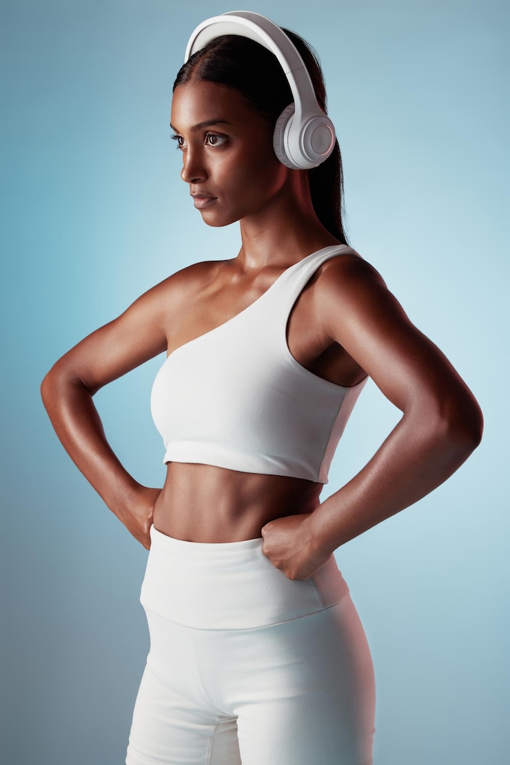 Foto fitnessstudio en vrouw die muziek streamt klaar om te beginnen met training en lichaamsbeweging in india mumbai focus blauwe achtergrond en gezond meisje atleet luisteren naar radio of mindset podcast