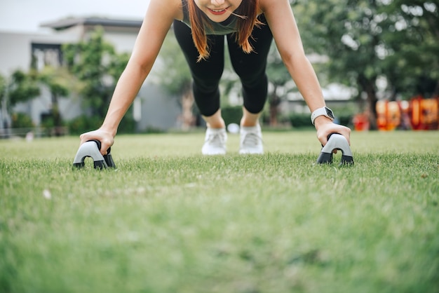 Fitnesstraining buiten, vrouw doet push ups in het park.