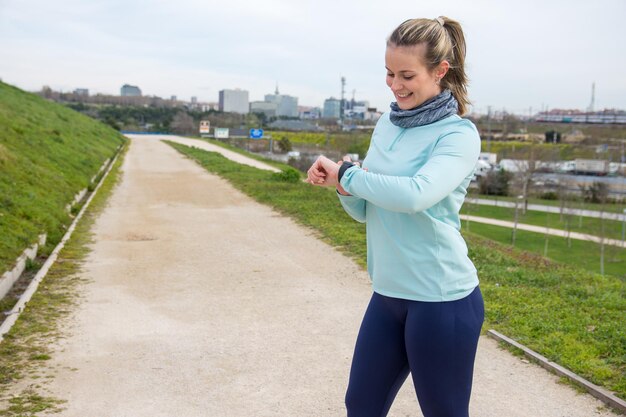 Foto fitnessvrouw die een pauze neemt en haar sporthorloge bekijkt