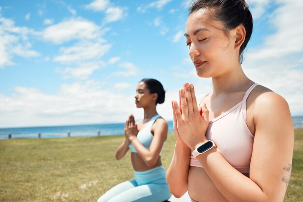 Fitnessyoga en vrouw in spirituele wellnessoefening en trainingstraining voor mentaal welzijn in de natuur Vrouwen in meditatie poseren op gras in kalme vrede en zen voor een gezonde geest, lichaam en geest