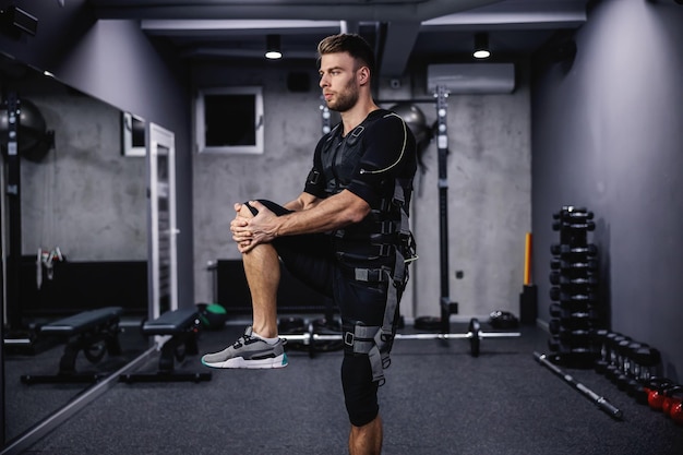 Fitte man in het elektrische gespierde pak in het trainingscentrum