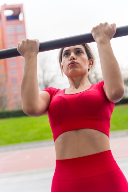 Fitte vrouw in rode outfit die armoefeningen doet in een parkfitness en gezond actief concept