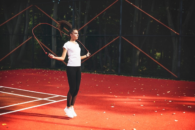 Fityoung woman skipping with a jump rope outdoors in a sport park in the morning.