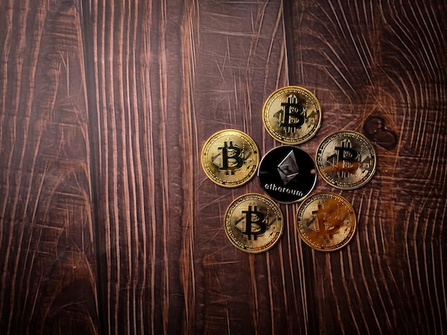 コピー スペースを持つ木製のテーブルに銀のイーサリアム デジタル暗号コインの中心を持つ 5 つの美しい黄金のビットコイン
