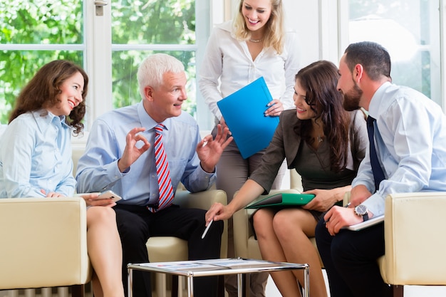 Five business people in team meeting studying graphs