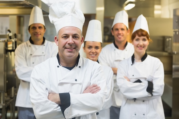 Cinque cuochi che indossano uniformi in posa in una cucina