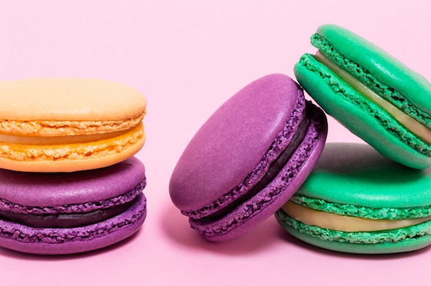 Five colored macaroons on a pink background.