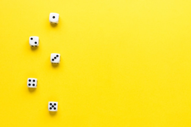 Photo five dice on yellow background. playing cube with numbers. items for board games. top view, flat lay. copy space.