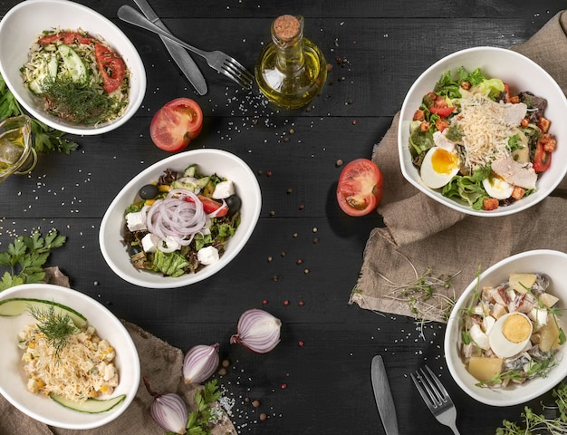Five different salads on black wooden table