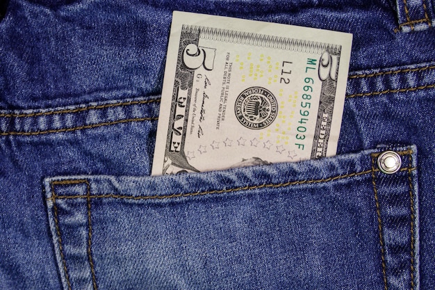 Five dollars banknote in the pocket of blue jeans