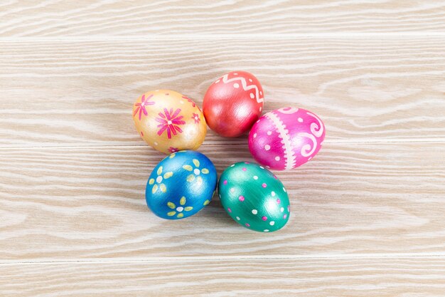 Five easter eggs trendy colored classic blue, green, orange, magenta and golden decorated on white wooden table.