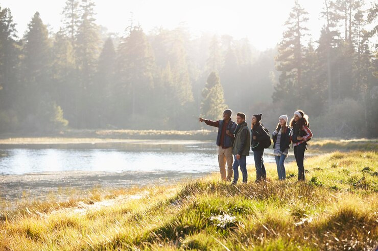 Photo five friends walking near a lake take in view one points
