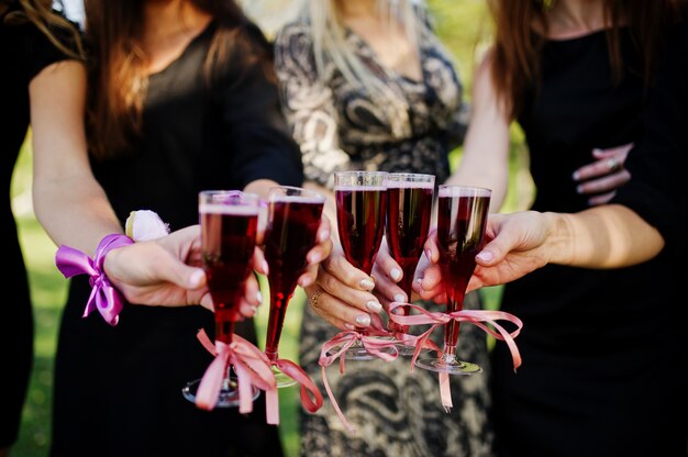 Five girls wear on black with balloons drinking red champagne at hen party.