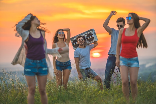 The five happy people dancing on the hill on the sunrise background