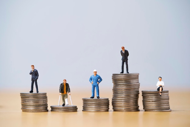 Five miniature figure in each career standing to different high\
and low coins stacking for variation of income or salary in each\
job concept