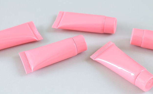 写真 灰色の表面のクローズアップに5つのピンクの化粧品チューブ。スパ製品の容器のデザイン