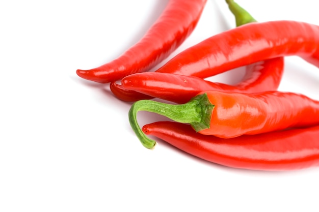 Five red chilli peppers closeup on white background