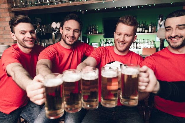 Five sports fans drinking beer in bar.