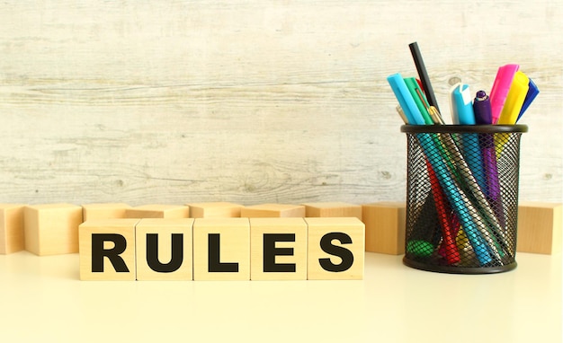 Five stacked wooden cubes with letters RULES on a white desktop on a gray background