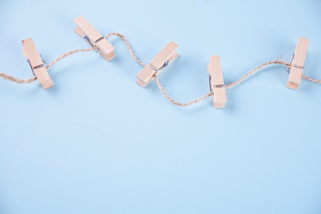 Five wooden clothespins on a rope on blue background