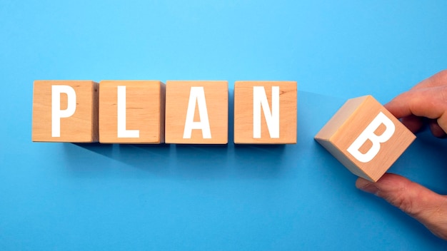 Five wooden cubes representing the word PLAN B isolated on a blue background