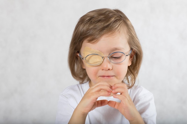 Five years old boy with one eye covered by eye pad and with eye glasses.