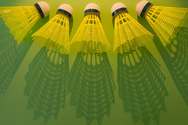 Photo five  yellow shuttlecocks with shadow on a green background with copy space