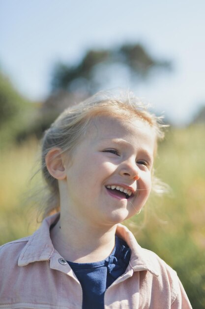 A fiveyearold girl laughs outside in the summer